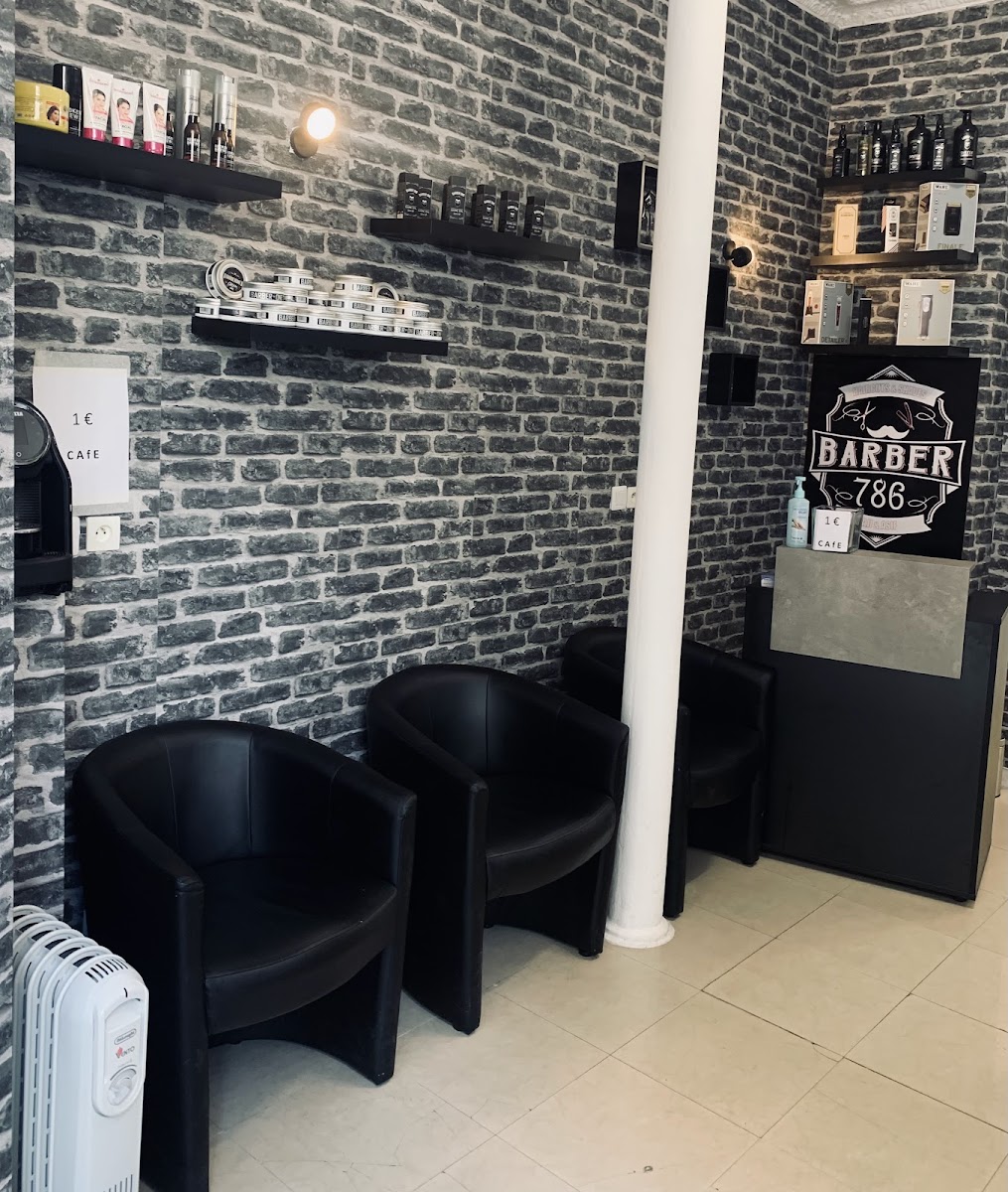 L'espace d'attente de Barber 786, mur en briques grises et fauteuils noirs